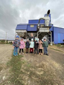 Дети с Натальей Васильевной на фоне  предприятия