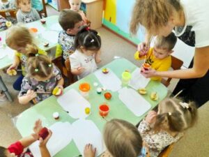 дети рисуют овощи и фрукты, воспитатель Матвеева Е.А. помогает детям 