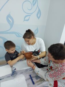 Воспитанники с родителями и воспитателем Пивоваровой Яной Петровной в процессе украшений готовых глиняных изделий